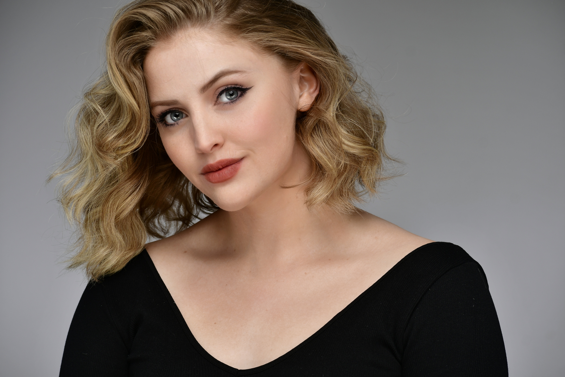 Blonde actress headshot with wavy hair in black v-neck, NYC by Dorothy Shi