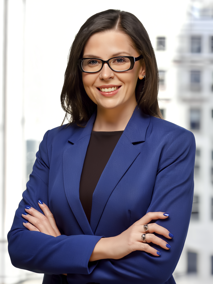 Corporate headshot of a woman in a blue blazer with NYC skyline backdrop