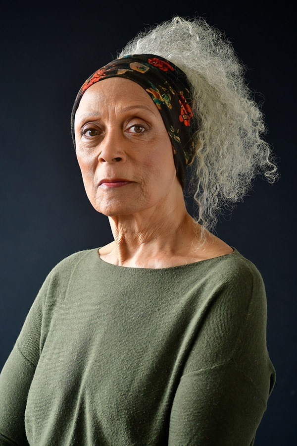 Mature actress character headshot with floral headwrap and green top, NYC