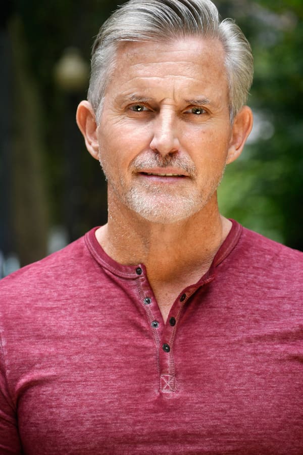 Mature male actor headshot with silver hair in red henley outdoors, NYC