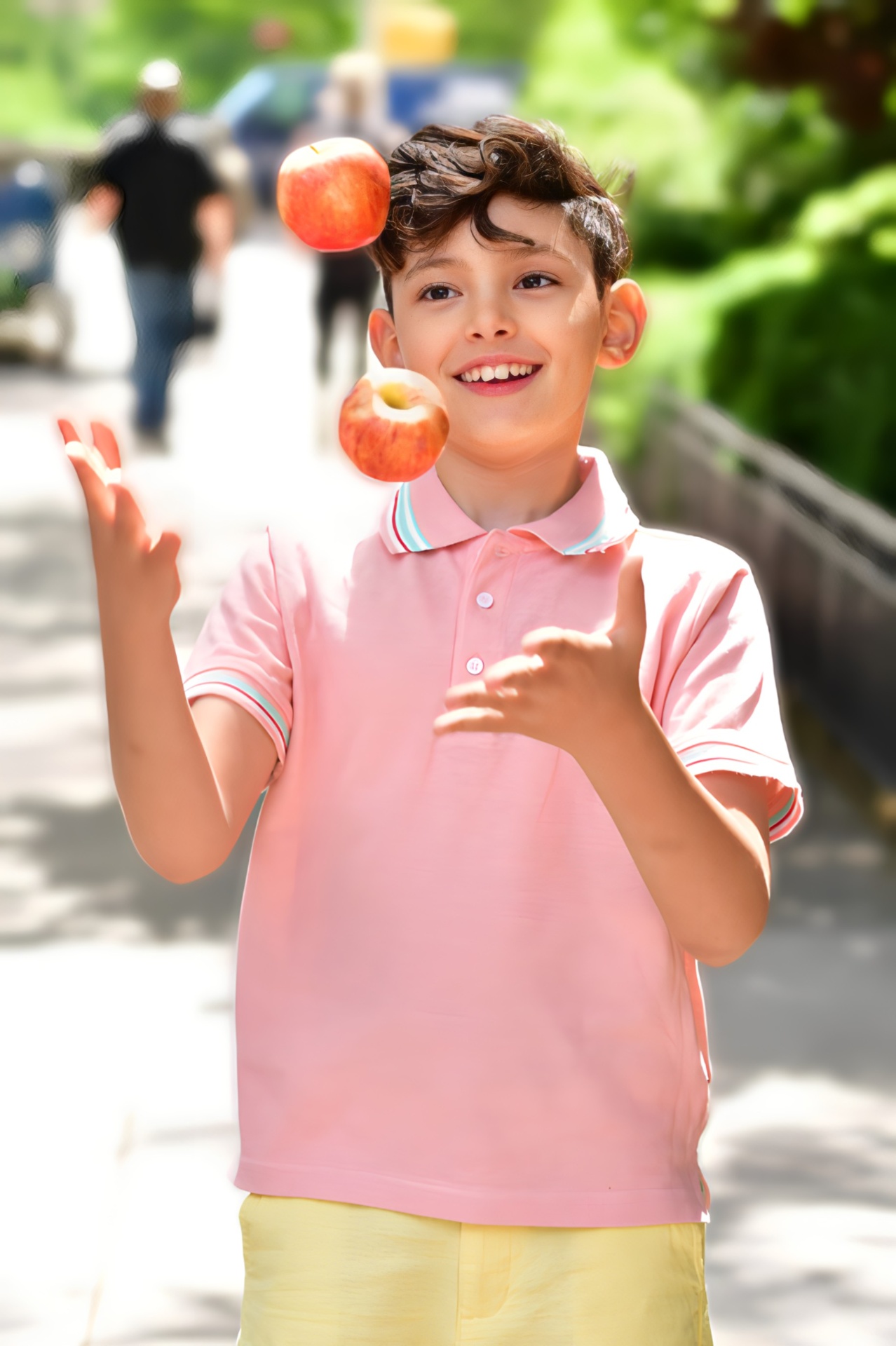 Boy juggling apples in pink polo on NYC street — child lifestyle photography