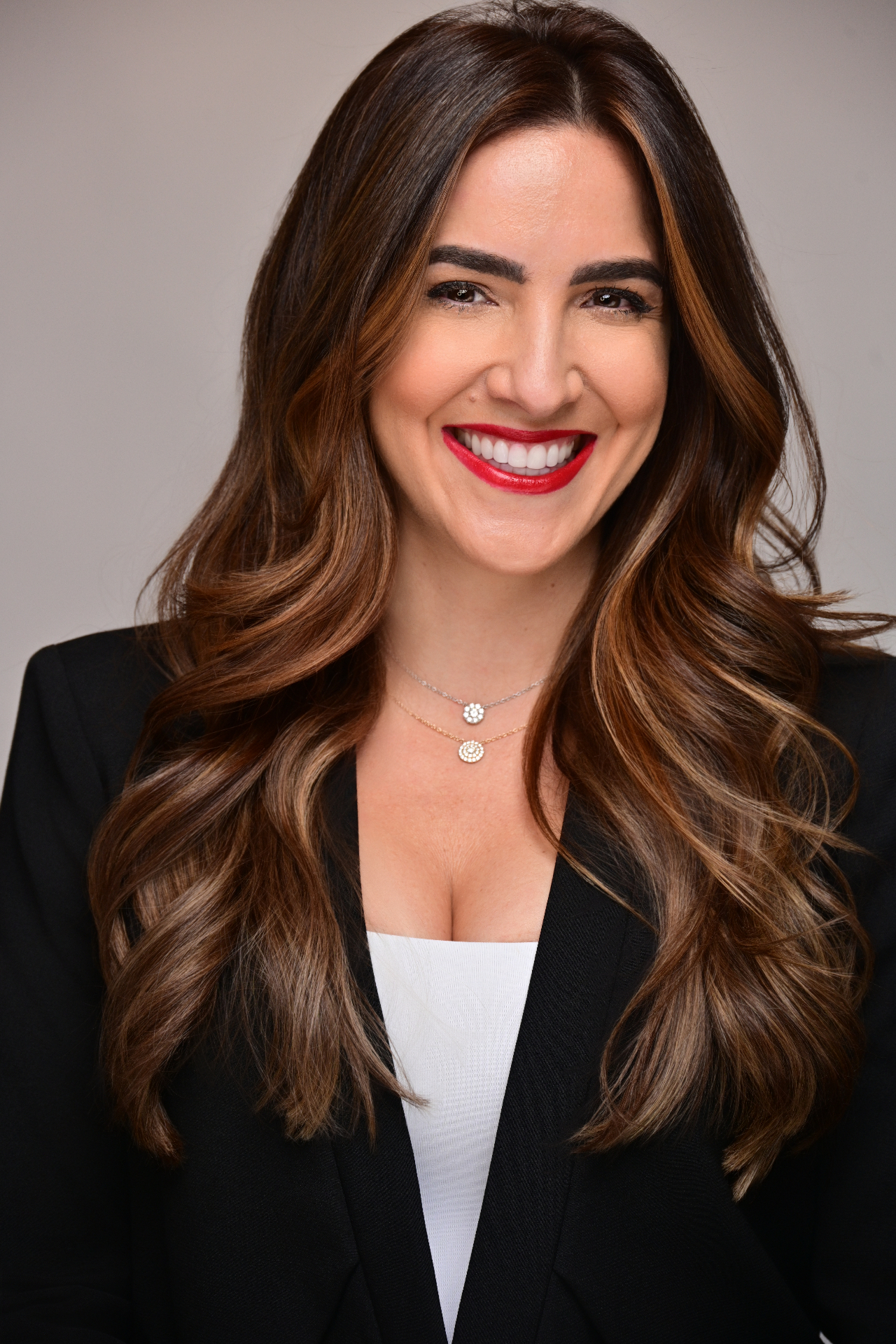 Studio corporate headshot of a woman with long brunette hair in a black blazer