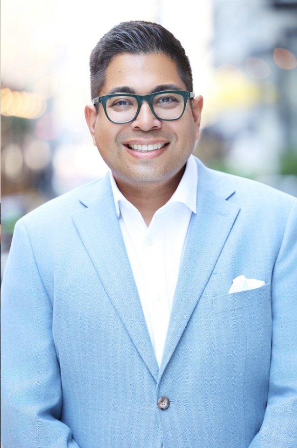 Corporate headshot of a man in a light blue blazer
